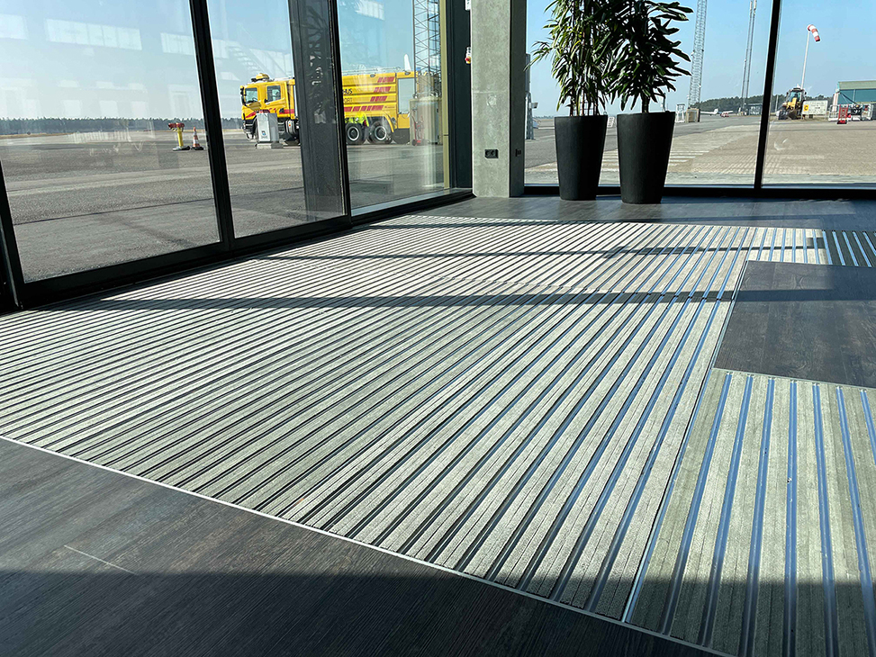 Stor indgangsmåtte i grå med striber i Aarhus Lufthavn