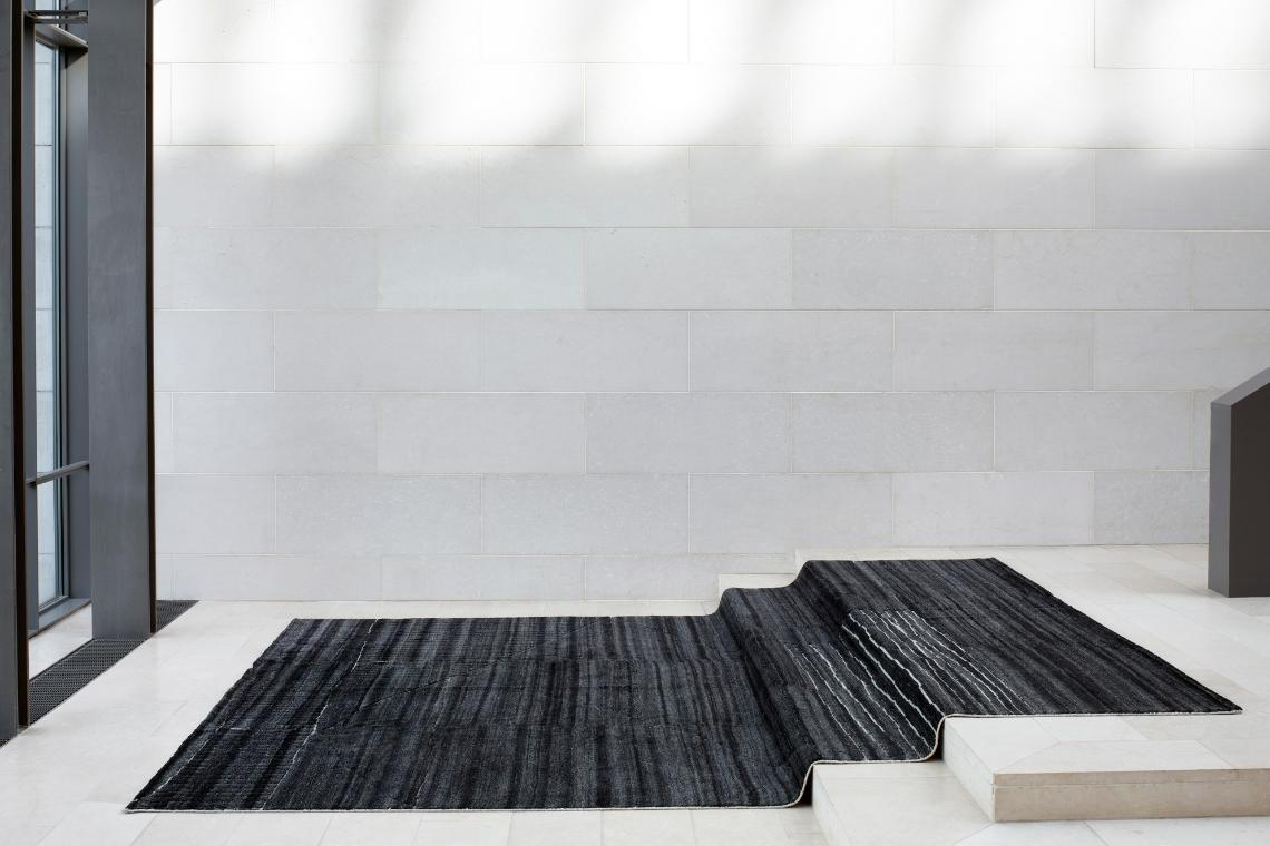 Løse tæpper fra Reza ligger på hvid trapper i moderne kontorbygnings indgangsparti